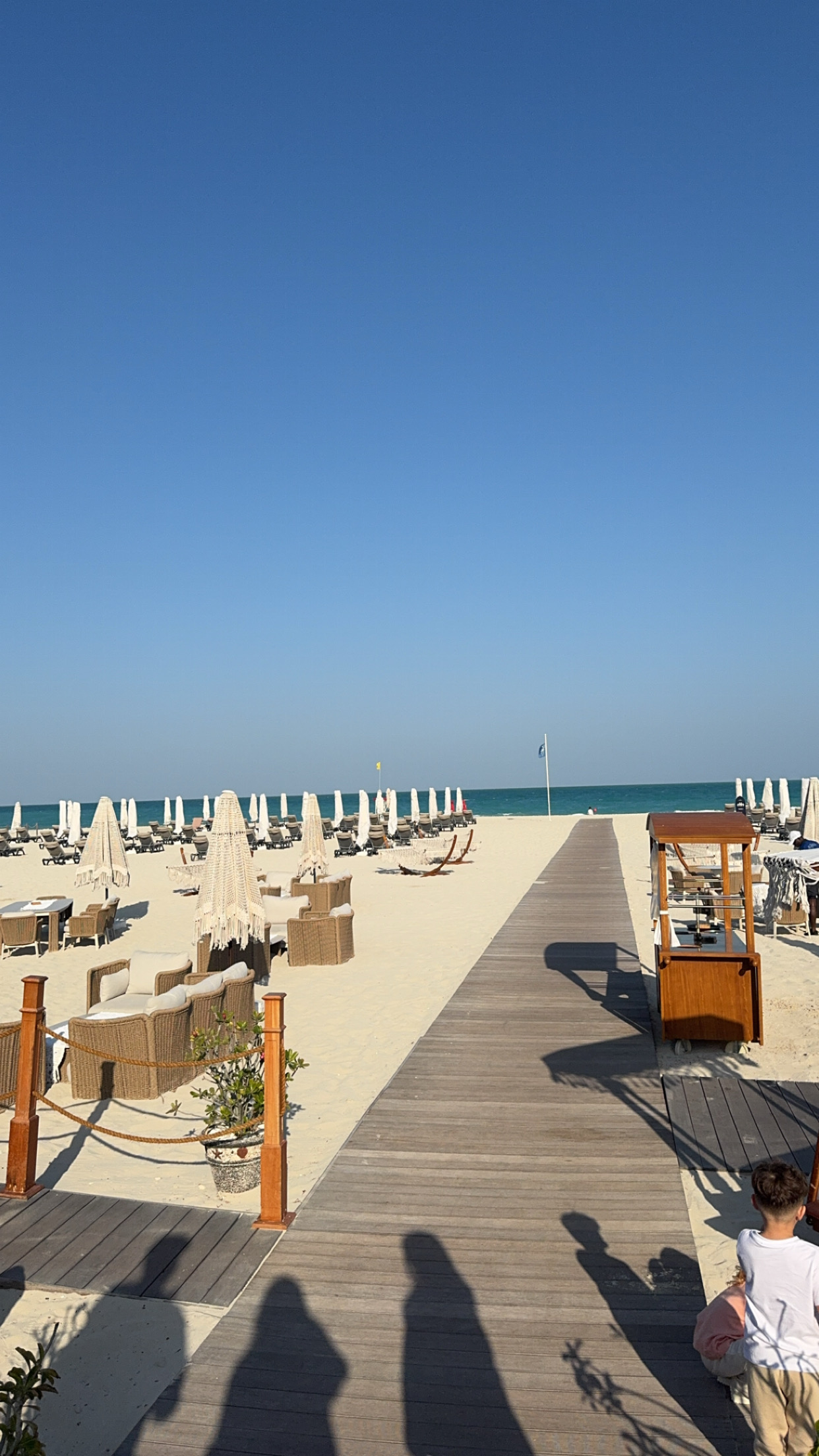 Fringed parasols and wicker furniture along the beach club boardwalk
